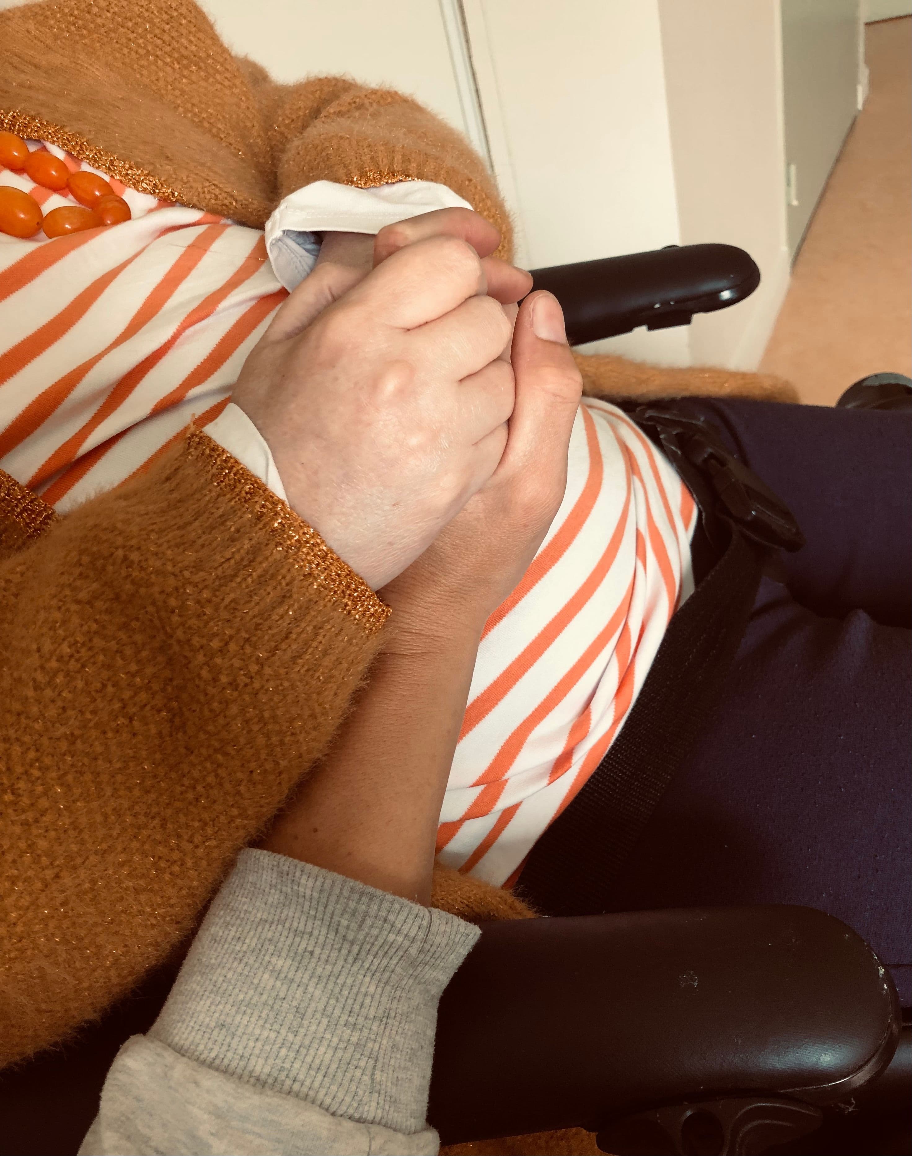 Main tenue par une personne en fauteuil, massage adapté