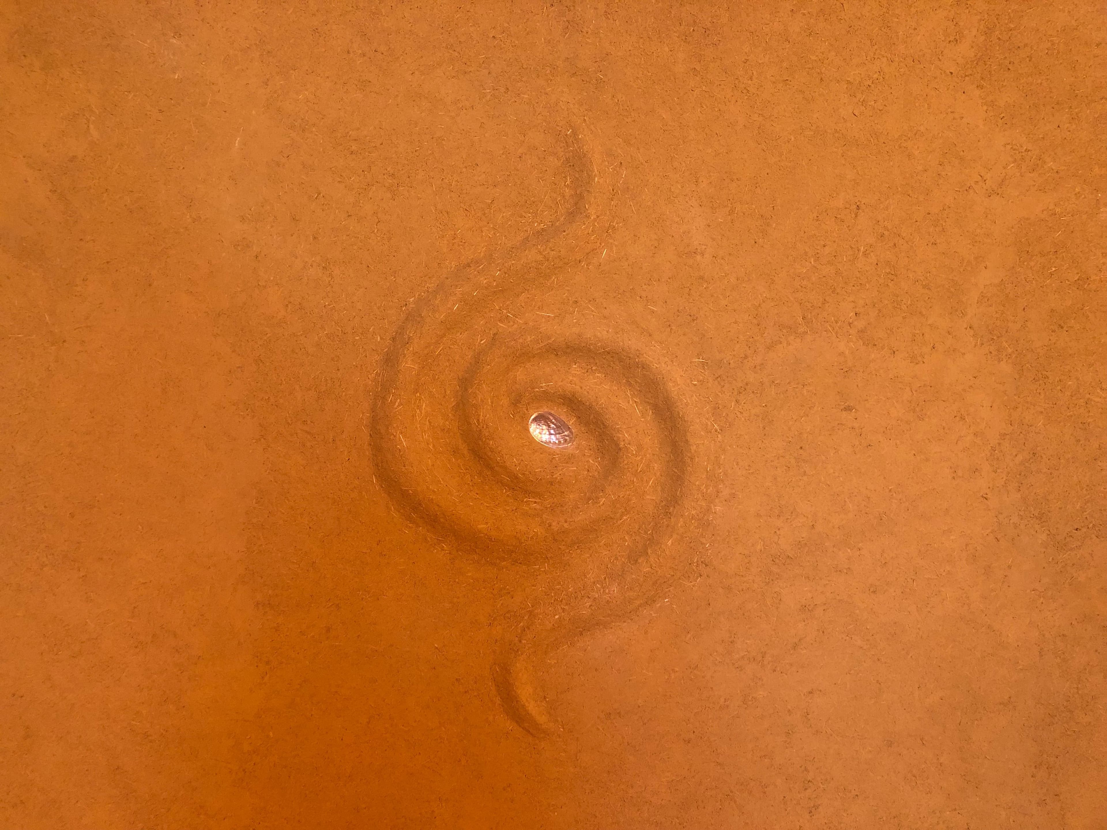 Mur en terre avec spirale en bas-relief, cabinet de massage